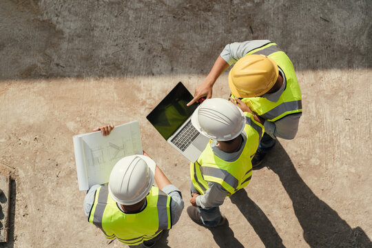 Top view, Team engineer building inspection use computer laptop and blueprint working at construction site. Teamwork discussing at workplace..