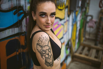 Young beautiful tattooed woman and graffiti street photography