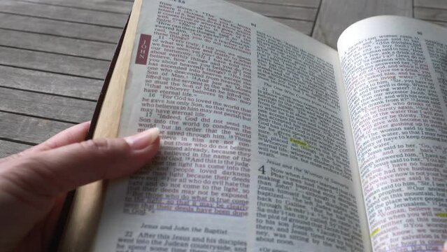 Turning the page of the bible to the passage of John 3:16 of the new testament. Close up view.
