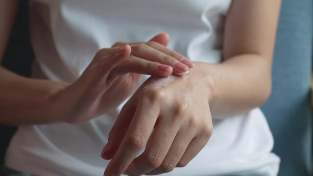 Close up of woman hand holding and applying moisturiser.