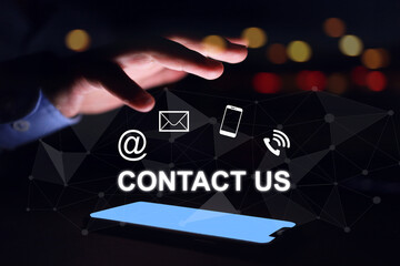 Contact us concept. Businessman hand above smart phone light screen with contact icon email social media chanel online devices. Question information customer services and products inquiry information