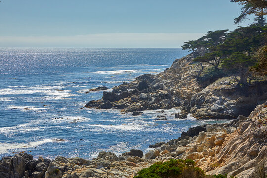 Rugged coastline and ocean along 17-Mile Drive in Pebble Beach on Monterey Peninsula on a foggy and sunny day
