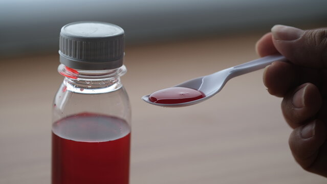 a bottle and spoon of cough syrup.