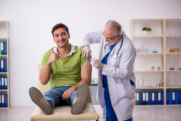 Young male patient visiting old male doctor in vaccination conce