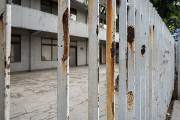 White and rusty fence of an abandoned house.