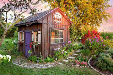 Cozy Little Cottage Garden Shed in Grassy Flower Beds at Sunset