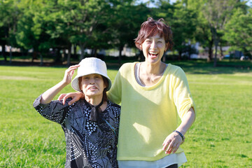 娘と高齢の母親の親子。笑顔で自然の中を外出する