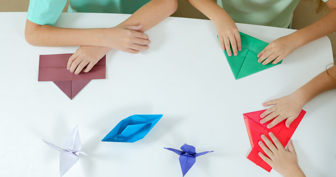 School children on vacation sit on the couch and fold origami 