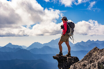 Adventurous athletic female hiker standing on top of a rugged mountain in the Pacific Northwest...