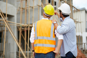 back workers or architect looking at construction site