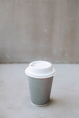 Portrait or vertical and selective focus shot of a cup of coffee on a disposable paper cup in a industrial cafe or coffee shop on isolated grey background