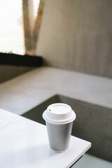 Portrait or vertical and selective focus shot of a cup of coffee on a disposable paper cup in a industrial cafe or coffee shop on isolated grey background