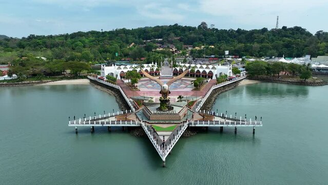 Aerial Panning Shot Of People By Eagle Statue At Dataran Lang On Sea Near Mountains - Langkawi, Malaysia