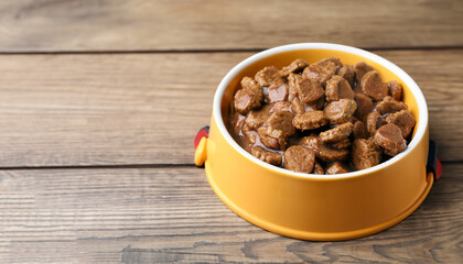 Wet pet food in feeding bowl on wooden table. Space for text