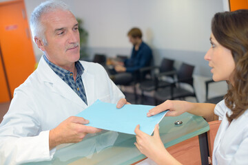 Doctor passing file to receptionist