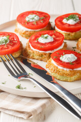 Fried zucchini in batter with creamy garlic sauce and fresh tomatoes close-up in a plate on the table. Vertical