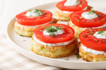 Pan fried zucchini in egg batter served with fresh tomato and creamy sauce close-up in a plate on the table. Horizontal