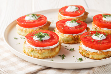 Fried zucchini with tomato, dill, mayonnaise and garlic sauce close-up in a plate on the table. Horizontal