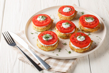 Summer snack of zucchini in egg batter with creamy garlic sauce and fresh tomatoes close-up in a plate on the table. Horizontal