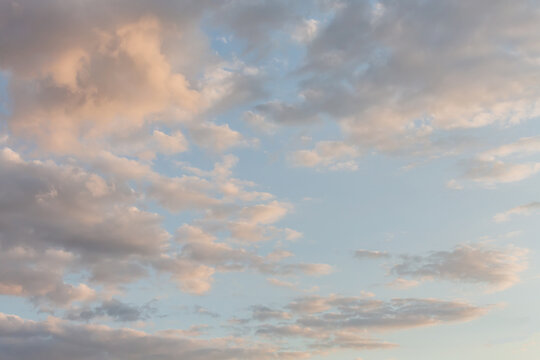 Beautiful fluffy clouds painted in bright painterly colors at sunrise. Multicolor background or wallpaper