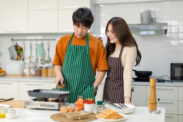 Asian young lover couple husband and wife in casual outfit with apron standing smiling while man...