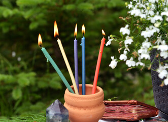 Still life with colorful burning candles on the witch table in the garden. Occult, esoteric and...