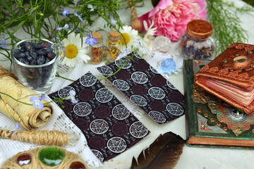 Still life with tarot cards, old decorated book of spell and magic wand on the table. Occult, esoteric and witchcraft concept. Mystic wicca background with vintage objects