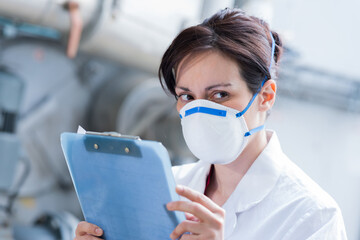 woman wearing dust mask and holding clipboard