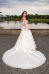 Fototapeta na wymiar Beautiful bride in wedding dress posing on sunset near lake