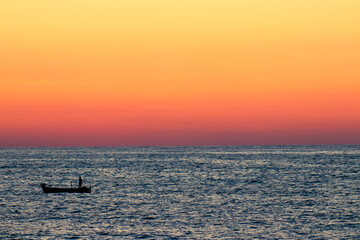 Naklejka premium Scenic view of sunset orange sky in peaceful sea bay with silhouette of lonely kayak. Trabzon,Turkey