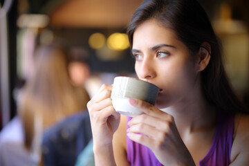 Pensive woman drinking coffee or tea in a restaurant