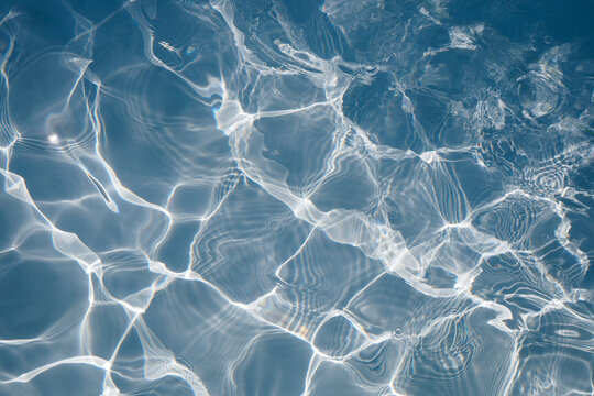 Blue water surface with bright sun light reflections, Swimming pool background