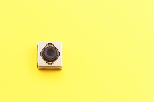 A miniature digital camera of a mobile phone on a yellow background