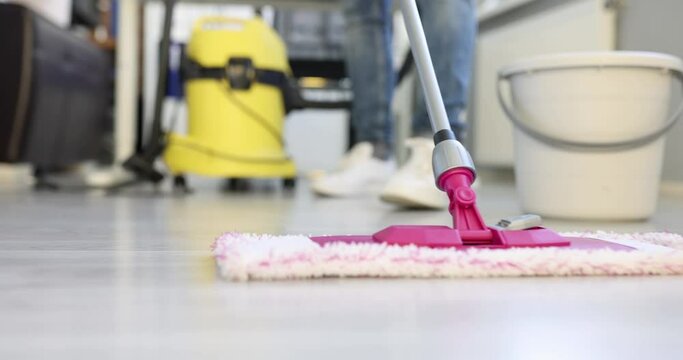 Woman uses flat wet mop cleaning floor in house. Cleaning services and home cleanliness