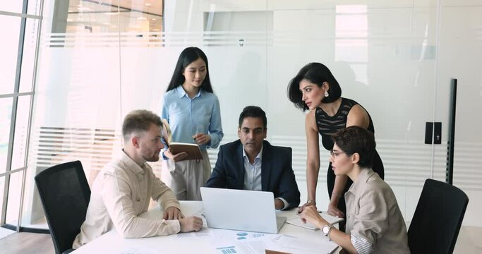 Group of diverse professional businesspeople meeting in modern office boardroom working on joint project use laptop. Creative business team discuss new app, analyse data, planning marketing strategy