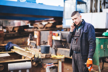 Fototapeta na wymiar Manual worker talking on mobile phone in shipyard construction site.