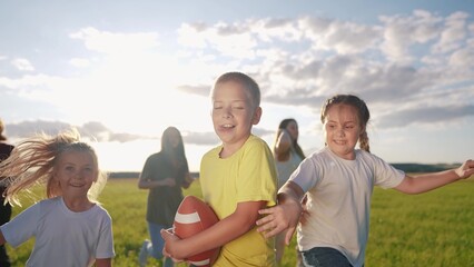 children playing rugby in the park. a group of children play american football run outdoors lifestyle in the park in summer. happy family kid dream concept. family children play american football run