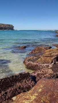 HD Video -Vertical orientation- Panning around from the bay to the sand at Wattamolla Beach on a beautiful spring day, on the ocean coast of Royal National Park, NSW, Australia.