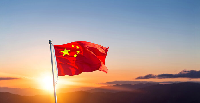 Chinese flag on pole waving in the wind against sunrise sky