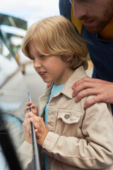 Vertical side view portrait of little boy choosing ice cream at market stall in amusement park