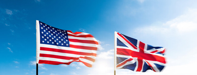 USA and Britain flags against blue sky background