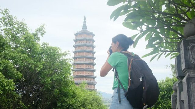 Female traveler photographing historic bai dinh pagoda, sprawling buddhist complex nestled in ninh binh province, representing vietnamese architectural and spiritual heritage