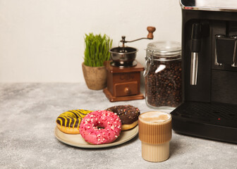 Modern coffee machine with a cup and donut on the kitchen table. Coffee house. Modern espresso coffee machine with a cup in the kitchen. Preparation of a fragrant hot drink. Place for text.Copy space.