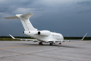Fototapeta na wymiar Modern white private jet on the airport apron on a cloudy day