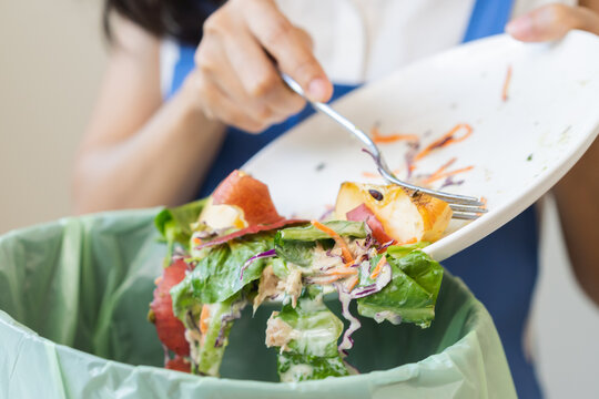 Compost from leftover food asian young housekeeper woman, female hand holding salad bowl use fork scraping waste, rotten vegetable throwing away into garbage, trash or bin. Environmentally responsible