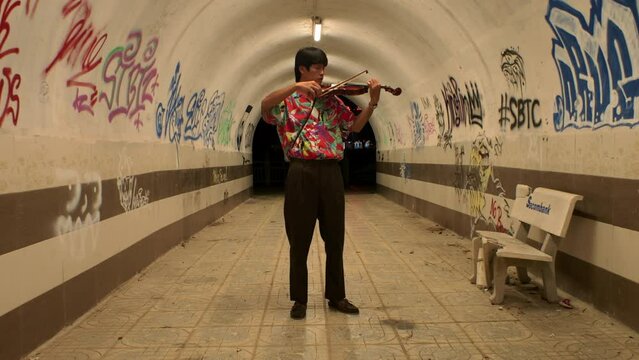 Captivating scene of musician playing melodic tunes on violin in graffiti tunnel
