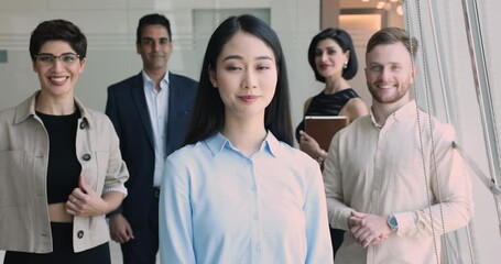 Smiley successful young Asian woman, team leader, boss, female intern, new employee posing in office with group of diverse motivated colleagues. Company management portrait, leadership, career growth