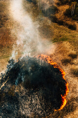 Aerial View Of Dry Grass Burns During Drought And Hot Weather. Natural Disaster. Concept Of Save Nature. Bush Fire And Smoke In Meadow Field. Wild Open Fire Destroys Grass. Nature In Danger.