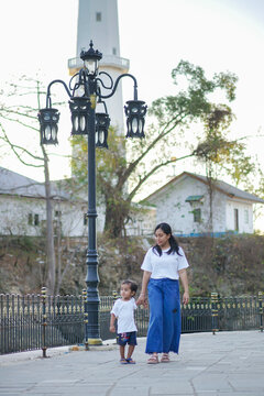 a mother holding her child's hand on a city street