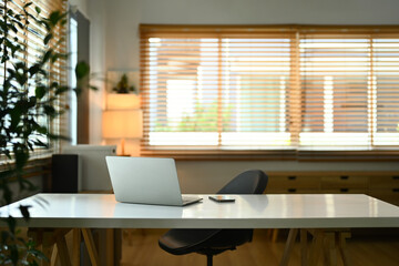 Comfortable workplace, white work desk with laptop and smartphone interior of cozy home office.